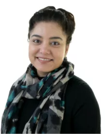 InspireHM— A person with dark hair is smiling while wearing a patterned scarf and a black top against a white background.