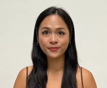 Nervelle Ngoh - general psychologist (autism) 1 InspireHM— A woman with long black hair and a neutral expression stands against a plain white background. She is wearing a sleeveless top, hoop earrings, and a delicate necklace.